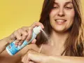 Donna sorridente applica latte solare spray SPF 50. La scelta di quale crema solare scegliere è facile con questo prodotto.