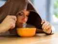 Donna inala vapore da una ciotola, usando un asciugamano per creare una sauna facciale. Un rimedio naturale per sciogliere il catarro.