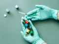 Mani guantate preparano fiale colorate, una siringa in mano, forse per il rocefin principio attivo.