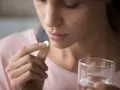 Donna con una compressa in mano e un bicchiere d'acqua. Triatec a cosa serve? Per alleviare il dolore.