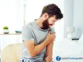 Uomo con barba che si tiene il braccio sinistro, avvertendo un fastidioso formicolio.