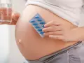 Pancia di donna incinta con blister di pillole blu e bicchiere d'acqua. Essenziale acido folico prima della gravidanza per la salute.