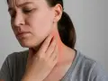 Donna con mano sul collo arrossato, preoccupata per i sintomi cervicali.