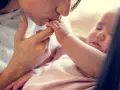 Dolce bacio di una madre al suo neonato. La protezione e l'amore per i neonati sono fondamentali, soprattutto contro malattie come la pertosse.