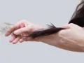 Mani che mostrano perdita capelli allattamento, cercando rimedi naturali per rinforzare i capelli indeboliti.