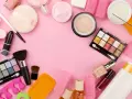 Tanti prodotti per il make-up, tra cui ombretti, rossetti e pennelli, disposti su sfondo rosa. Attenzione, gli ombretti scadono!