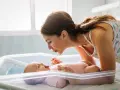 Mamma sorride al suo neonato nella culla. Un momento dolce che fa pensare a cosa mangiare dopo il parto per recuperare le energie.