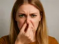 Donna con espressione disgustata che si tappa il naso, forse per un sederino rosso per cacca acida.