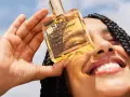 Una mano tiene una bottiglietta di Nuxe Huile Prodigieuse, un olio multiuso per viso, corpo e capelli. Scopri a cosa serve questo prezioso olio.