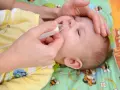 Mano che usa un aspiratore nasale su un neonato con naso chiuso senza muco.