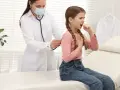 Bambina con tosse, uno dei sintomi della pertosse, visitata dal medico.