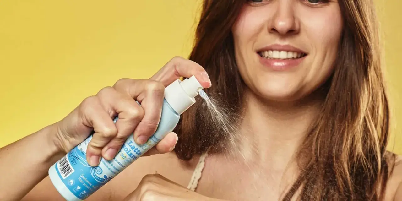 Donna sorridente applica latte solare spray SPF 50. La scelta di quale crema solare scegliere è facile con questo prodotto.