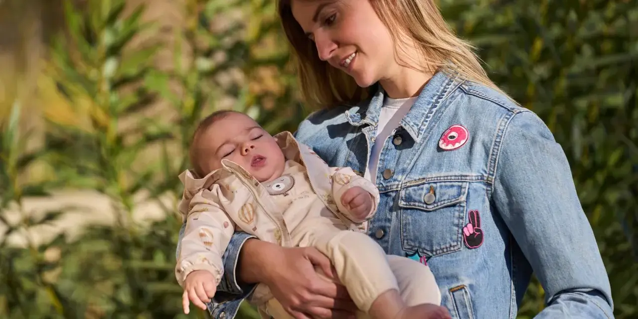 Mamma con bimbo in braccio, un'idea su come vestire i bambini in questo periodo con un morbido completo e giacca di jeans.