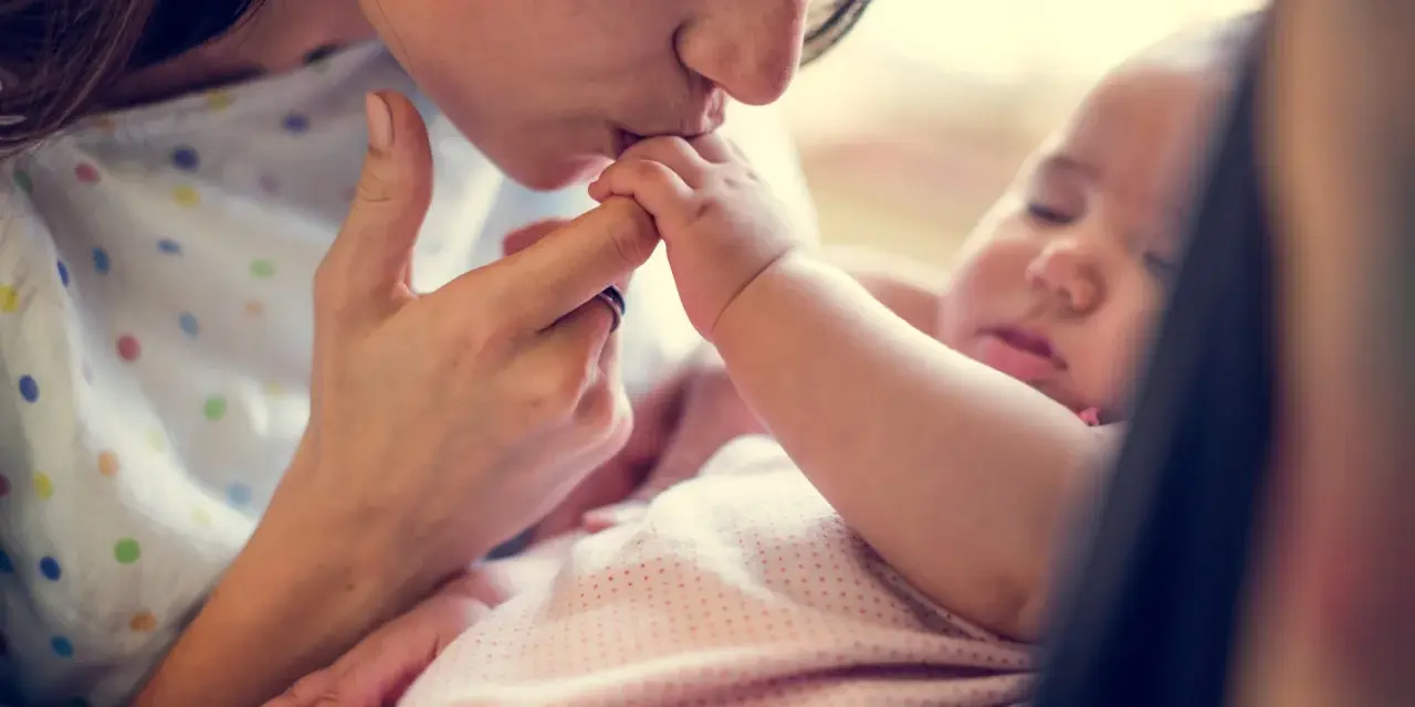 Dolce bacio di una madre al suo neonato. La protezione e l'amore per i neonati sono fondamentali, soprattutto contro malattie come la pertosse.