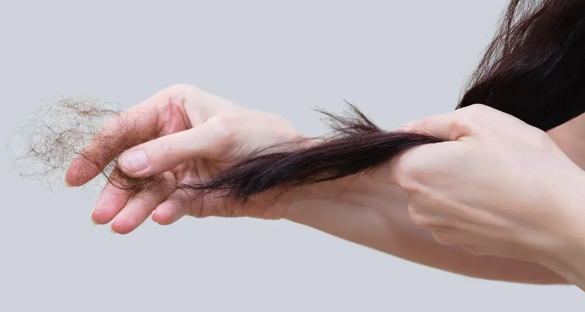 Mani che mostrano perdita capelli allattamento, cercando rimedi naturali per rinforzare i capelli indeboliti.
