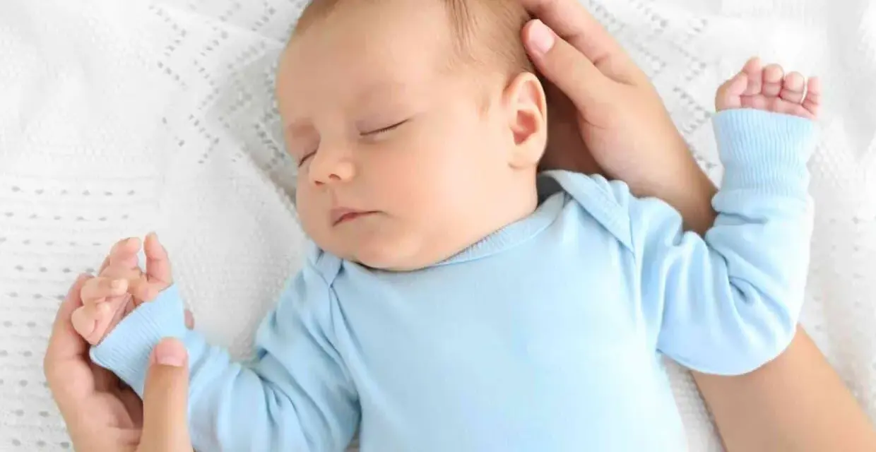 Un neonato dorme sereno sul petto della mamma, cullato dalle sue mani.