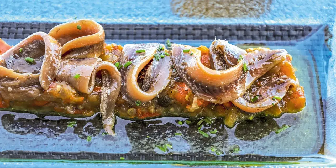 Alici sott'olio su un letto di verdure, un piatto gustoso e nutriente, perfetto anche se si possono mangiare le alici sott'olio in gravidanza.