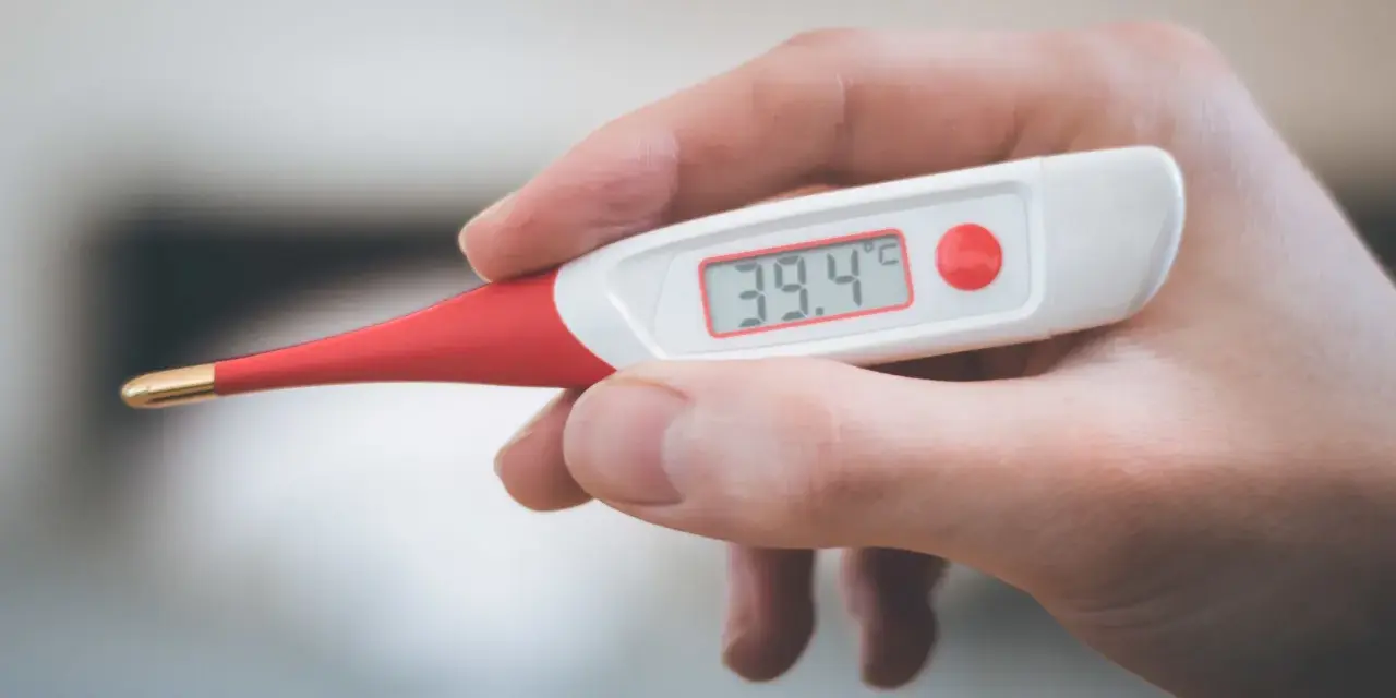 Termometro digitale mostra 39.4°C. Febbre alta, serve antibiotico e tachipirina.