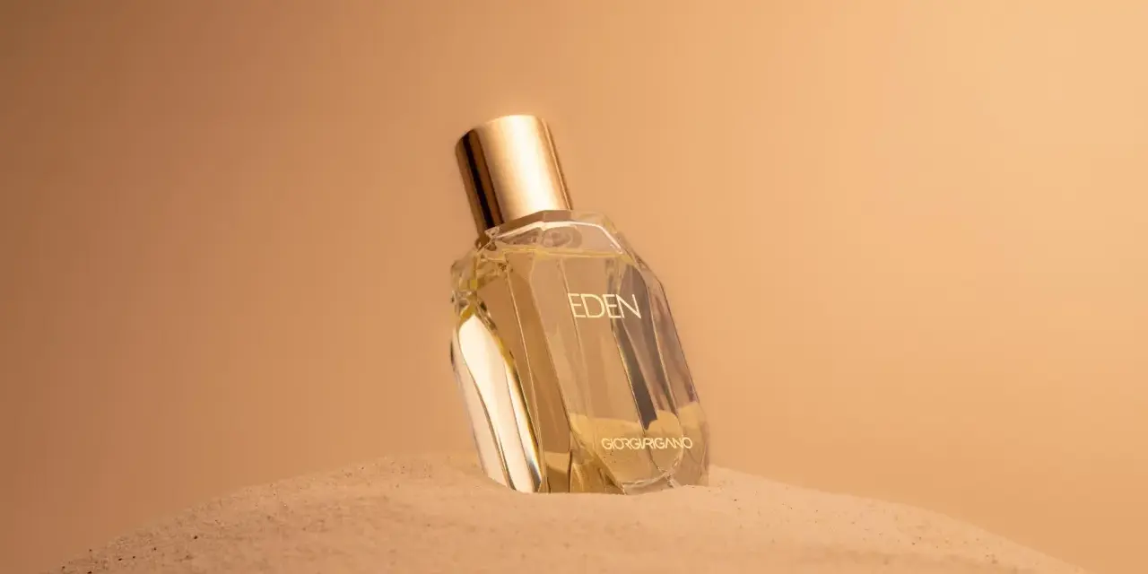 Flacone di profumo "Eden" su sabbia dorata. Un body mist cos'è? Una fragranza leggera per rinfrescarsi.