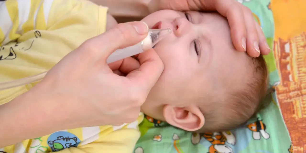 Mano che usa un aspiratore nasale su un neonato con naso chiuso senza muco.