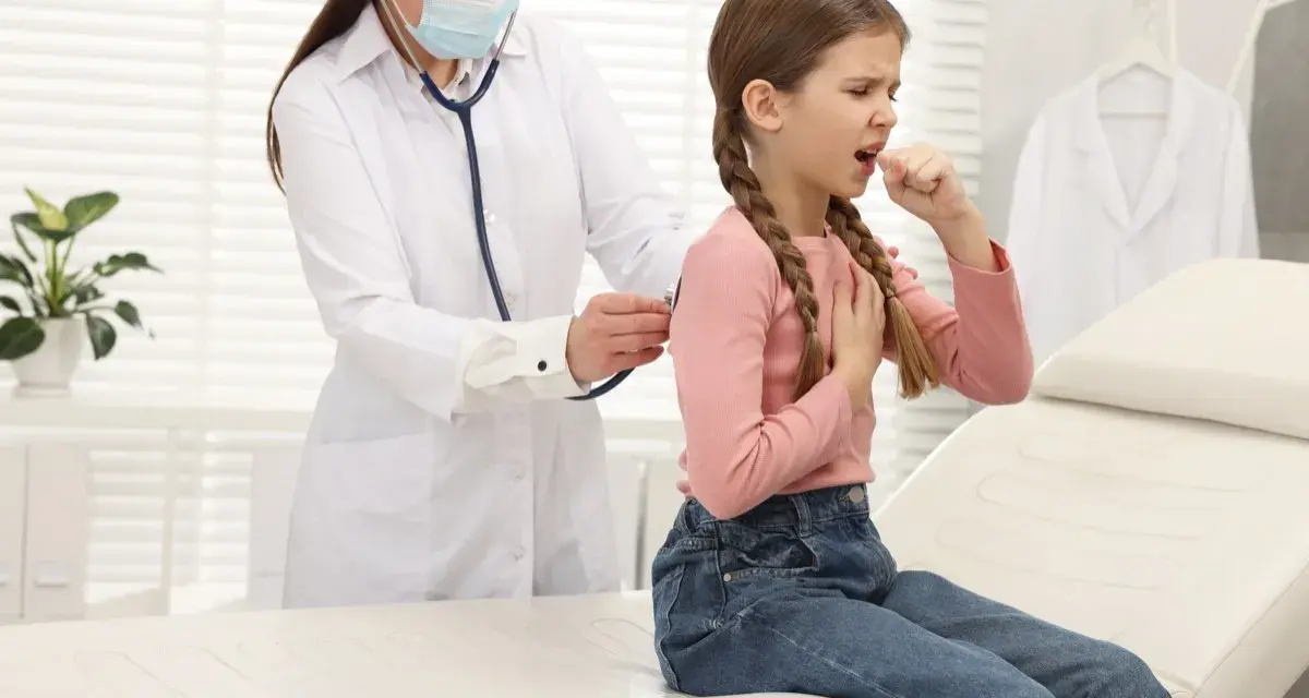 Bambina con tosse, uno dei sintomi della pertosse, visitata dal medico.