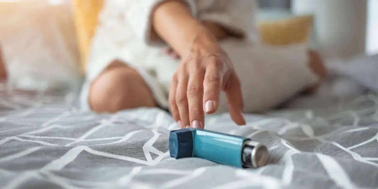 Mano tesa verso un inalatore blu, un aiuto per respirare. Il foster spray è pronto all'uso.