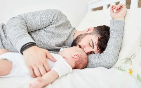 Padre e neonato nel lettone in sicurezza, un momento di dolce riposo e amore.