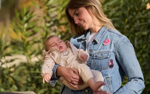 Mamma con bimbo in braccio, un'idea su come vestire i bambini in questo periodo con un morbido completo e giacca di jeans.