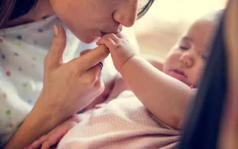 Dolce bacio di una madre al suo neonato. La protezione e l'amore per i neonati sono fondamentali, soprattutto contro malattie come la pertosse.
