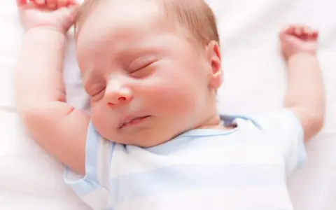 Un neonato dorme sereno con le braccia alzate. Sembra che i neonati possano mangiare mentre dormono, un vero miracolo della natura.