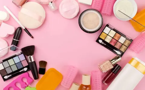 Tanti prodotti per il make-up, tra cui ombretti, rossetti e pennelli, disposti su sfondo rosa. Attenzione, gli ombretti scadono!
