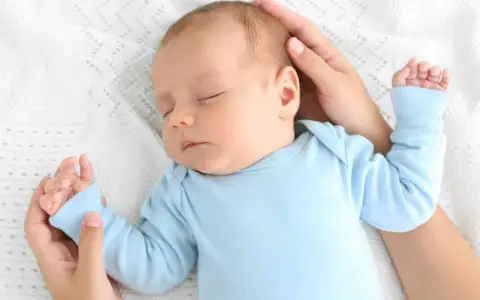 Un neonato dorme sereno sul petto della mamma, cullato dalle sue mani.