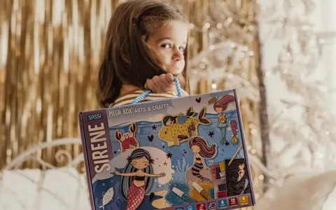 Bambina con scatola "Sirene Mega Box Arts & Crafts". A che età si impara a leggere? Forse con questo kit creativo, l'apprendimento sarà più divertente!