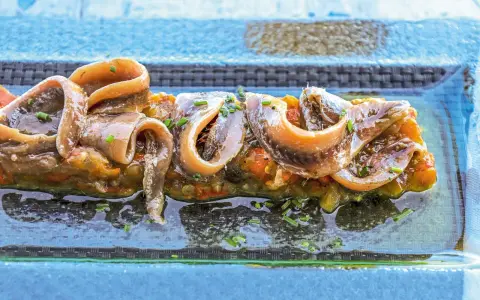 Alici sott'olio su un letto di verdure, un piatto gustoso e nutriente, perfetto anche se si possono mangiare le alici sott'olio in gravidanza.