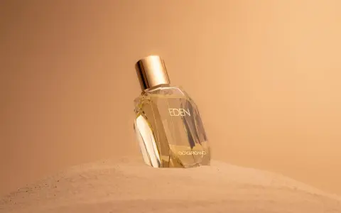 Flacone di profumo "Eden" su sabbia dorata. Un body mist cos'è? Una fragranza leggera per rinfrescarsi.