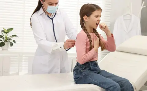 Bambina con tosse, uno dei sintomi della pertosse, visitata dal medico.