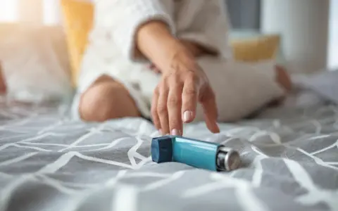 Mano tesa verso un inalatore blu, un aiuto per respirare. Il foster spray è pronto all'uso.