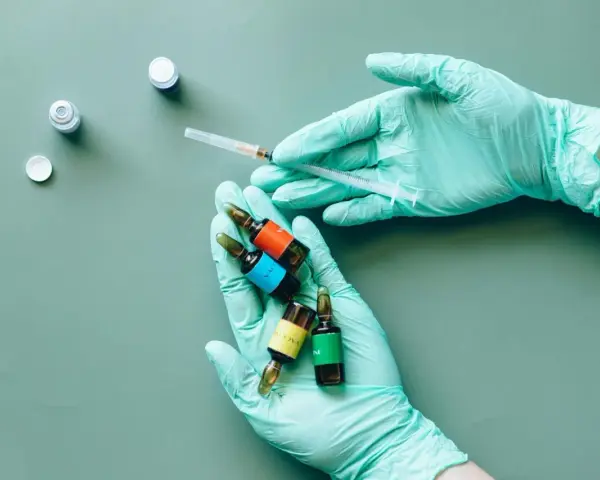 Mani guantate preparano fiale colorate, una siringa in mano, forse per il rocefin principio attivo.