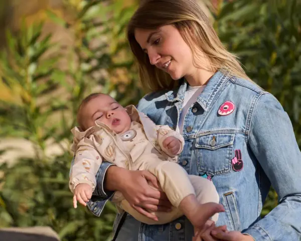 Mamma con bimbo in braccio, un'idea su come vestire i bambini in questo periodo con un morbido completo e giacca di jeans.