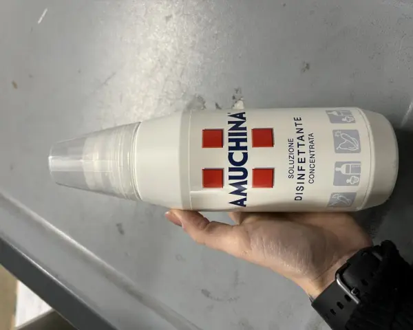 Mano tiene flacone Amuchina per disinfettare ciuccio. Soluzione disinfettante concentrata per igiene.