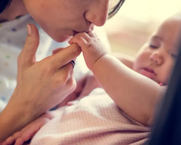 Dolce bacio di una madre al suo neonato. La protezione e l'amore per i neonati sono fondamentali, soprattutto contro malattie come la pertosse.