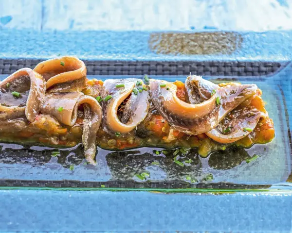 Alici sott'olio su un letto di verdure, un piatto gustoso e nutriente, perfetto anche se si possono mangiare le alici sott'olio in gravidanza.