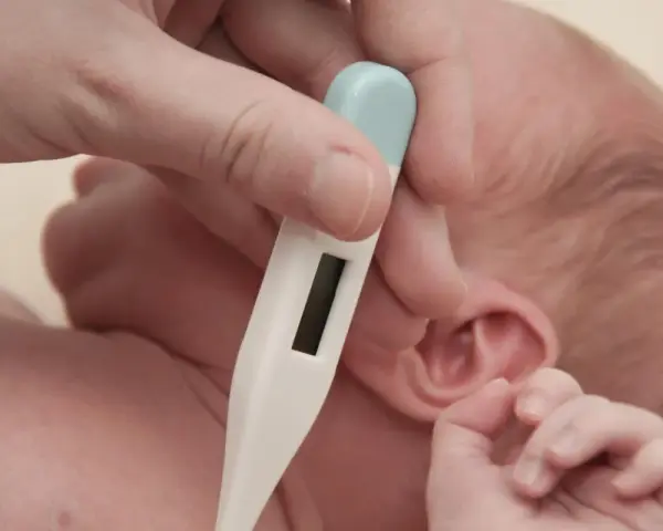 Misurazione della temperatura corporea neonato 4 mesi con termometro digitale.