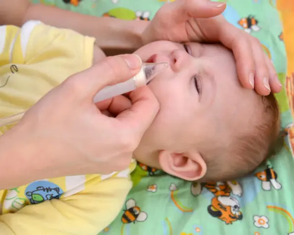 Mano che usa un aspiratore nasale su un neonato con naso chiuso senza muco.