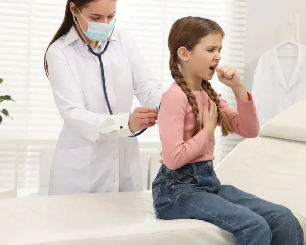 Bambina con tosse, uno dei sintomi della pertosse, visitata dal medico.