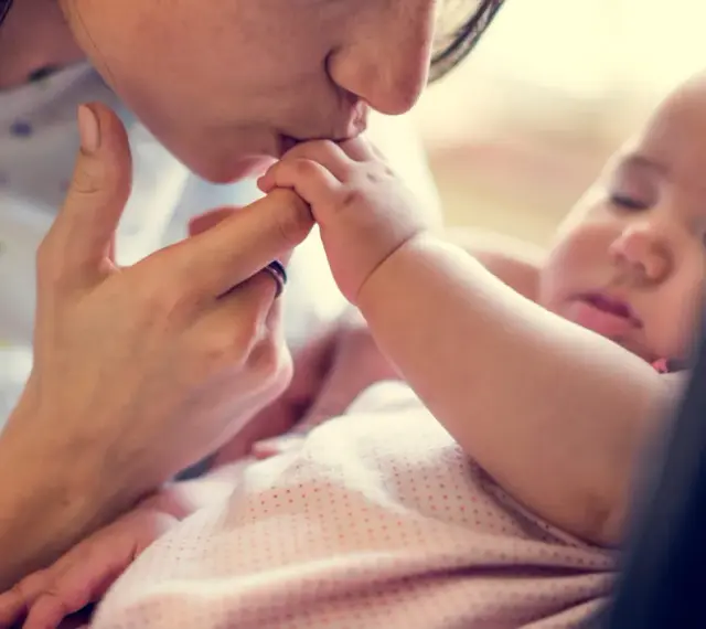 Dolce bacio di una madre al suo neonato. La protezione e l'amore per i neonati sono fondamentali, soprattutto contro malattie come la pertosse.