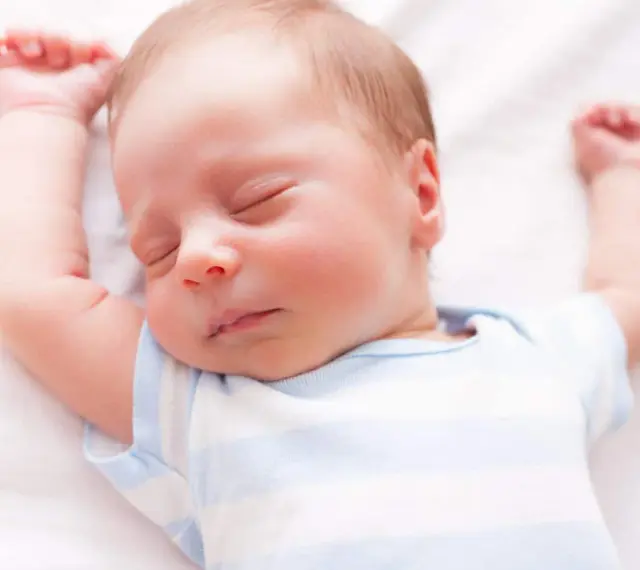 Un neonato dorme sereno con le braccia alzate. Sembra che i neonati possano mangiare mentre dormono, un vero miracolo della natura.