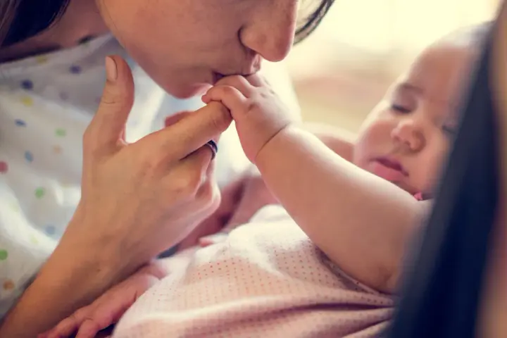 Dolce bacio di una madre al suo neonato. La protezione e l'amore per i neonati sono fondamentali, soprattutto contro malattie come la pertosse.