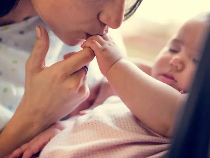 Dolce bacio di una madre al suo neonato. La protezione e l'amore per i neonati sono fondamentali, soprattutto contro malattie come la pertosse.