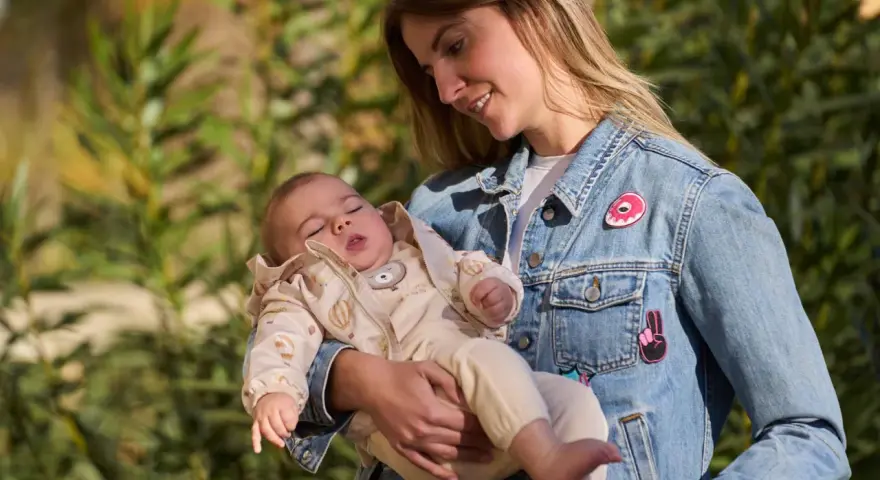 Mamma con bimbo in braccio, un'idea su come vestire i bambini in questo periodo con un morbido completo e giacca di jeans.